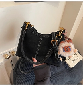 Close-up of black crossbody bucket bag with white contrast stitching and gold metal buckle