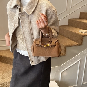 Close-up of vintage brown lychee grain leather handbag with gold buckle on stairs