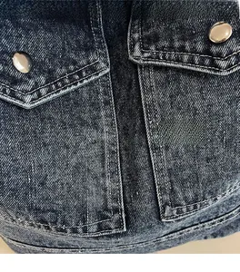 Detail of denim tote bag showing twill fabric texture, flap pocket, and silver metal button
