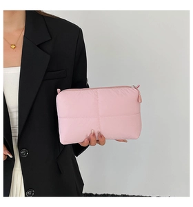 Vista detallada de las costuras acolchadas y la suave textura rosa de este neceser de maquillaje