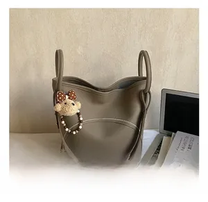 Detail of dark khaki litchi leather bucket bag with cute bear charm and zip accent