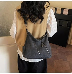 Détail du sac à bandoulière gris foncé mat avec zips parallèles porté par un mannequin