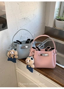 Gros plan sur les sacs seaux en cuir grainé rose et bleu avec charms ours