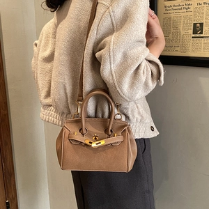 Detail of vintage brown lychee grain leather handbag with classic metal lock and strap