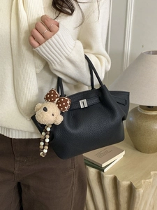 Minimalist black pebble leather bucket handbag with silver buckle and plush doll charm