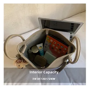Spacious interior of beige pebbled leather bucket bag holding a 13-inch laptop and cosmetics