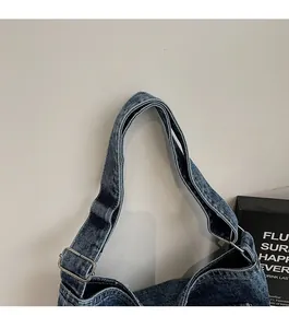 Close-up of wide denim shoulder strap with silver adjustable metal buckle on tote bag
