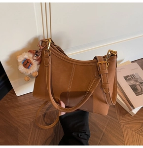 Detailed view of vintage brown suede bucket bag with adjustable strap and alpaca charm
