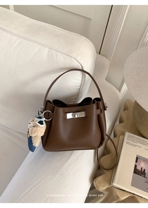 Détail du sac seau marron en cuir grainé avec fermoir rotatif et breloque petit ours