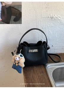 Gros plan sur le sac seau en cuir noir avec fermoir rotatif argenté et breloque ours
