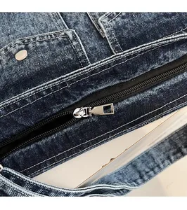 Detailed close-up of the smooth silver zipper and rivets on the blue denim tote bag