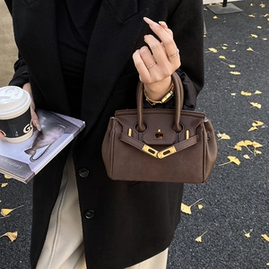 Close-up of deep brown lychee-patterned mini handbag with golden metal twist lock detail