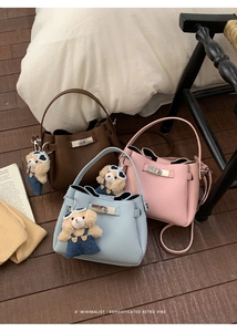 Trois sacs seaux en marron, bleu et rose avec breloques d'ours sur sol en bois sombre