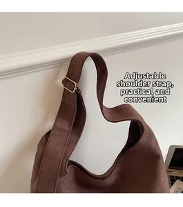 Detail of adjustable wide shoulder strap with gold buckle on brown suede hobo bag
