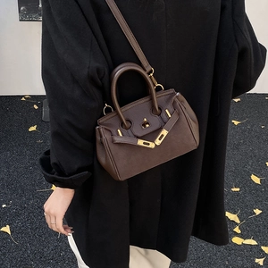 Macro shot of dark coffee lychee texture leather with gold turn-lock on the Kelly handbag