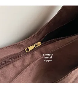 Detail of premium golden hardware zipper pull on dark brown faux suede shoulder bag