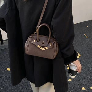 Close-up of dark brown lychee texture leather handbag on a chic urban model background