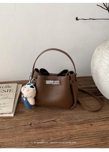 Détail du sac seau en cuir grainé marron avec fermoir rotatif argenté et charm ours