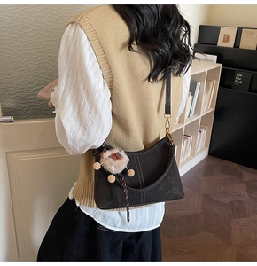 Detail of vintage dark brown bucket bag with lion plush charm and gold hardware on shoulder