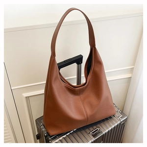 Detailed macro view of caramel lychee-grain leather texture on a spacious hobo shoulder bag