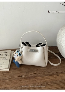 Détail du sac seau écru texture litchi avec fermoir argenté et breloque ours en peluche