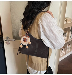 Dark brown leather bucket bag with white contrast stitching and a cute lion plush charm