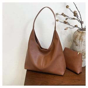 Brown litchi grain leather tote bag set with matching zipper pouch on wood surface