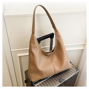 Close-up of brown hobo bag with litchi grain texture on a metallic suitcase