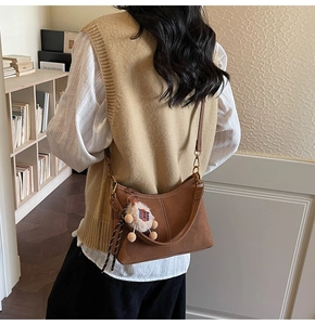 Detail of vintage brown leather bucket bag with lion plush charm worn by model