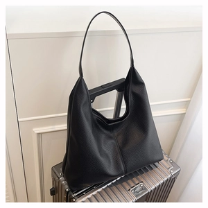 Close-up of black leather hobo bag with litchi texture on a silver suitcase