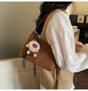 Close-up of brown matte leather bucket bag with white stitching and cute sheep charm
