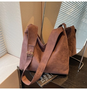 Detail of dark brown suede tote bag featuring a wide shoulder strap and vintage gold buckle