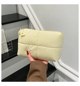 Detailed view of yellow quilted cloud clutch bag with cross-stitch pattern and zipper