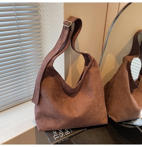 Detailed macro view of dark brown suede hobo bag texture and gold metal buckle strap