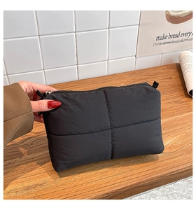 Primer plano detallado de un bolso de mano de nailon acolchado negro con cremallera superior