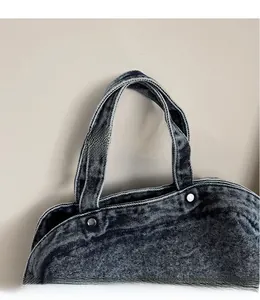 Gros plan détaillé du sac fourre-tout en denim bleu foncé avec rivets métalliques et coutures