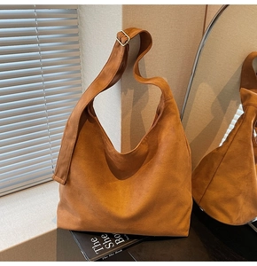 Detailed shot of brown suede tote bag with adjustable metal shoulder strap buckle