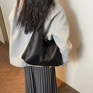 Close-up of black lychee grain leather texture and slouchy drape of the tote bag