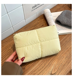 Primer plano de un bolso de mano acolchado amarillo con cremallera y textura suave