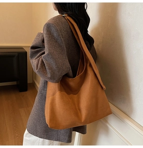 Detail of a large brown suede tote bag with a wide shoulder strap for daily commuting