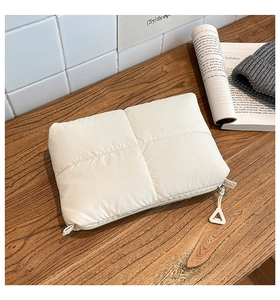 Detalle del bolso de mano acolchado blanco con cremallera y tirador triangular metálico