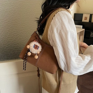 Brown leather bucket bag with white stitching and plush charm for daily commute