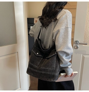 Detail of black denim tote bag featuring utility pockets and silver metal buckles