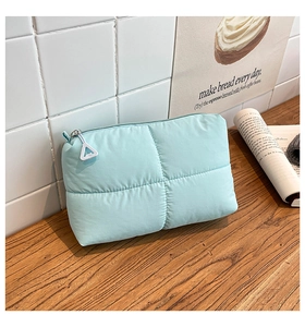 Primer plano de neceser acolchado verde menta con tirador de cremallera triangular blanco