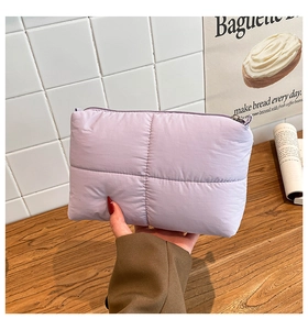 Detalle de cartera acolchada lavanda con cremallera metálica y textura suave