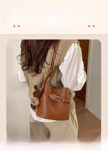 Détail du sac seau en cuir marron chaud avec boucle en métal et breloque ours en peluche
