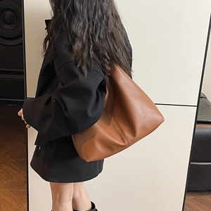 Detailed view of caramel brown pebbled leather tote bag worn as a shoulder bag