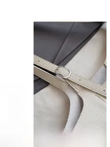 Close-up of beige lychee grain leather tote bag with silver buckle and adjustable strap