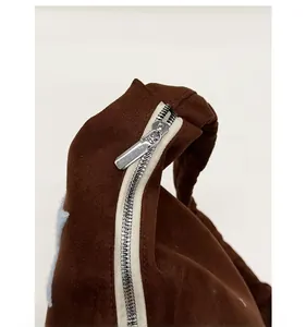 Detail shot of smooth silver zipper and suede texture on brown casual tote bag