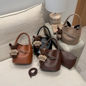 Détail du sac seau minimaliste avec boucle en métal et breloque ours en quatre couleurs
